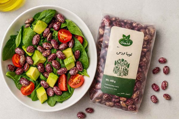 سالاد تازه با لوبیا عروس ارگانیک، آووکادو و گوجه در کنار بسته‌بندی لوبیا عروس آبگینه روی میز