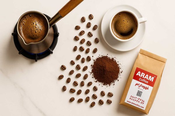 عکاسی فلت‌لی لوکس از قهوه ترک آرام؛ قهوه‌جوش روی شعله کم، فنجان با فوم، دانه‌ها و بسته بازِ محصول روی سطح سفید