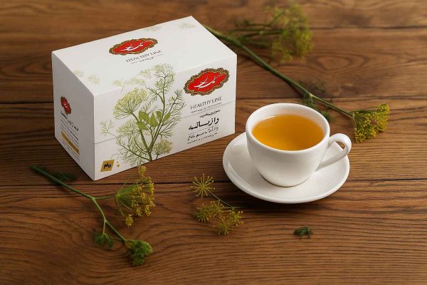 بسته دمنوش رازیانه گلستان و فنجان دمنوش روی میز چوبی