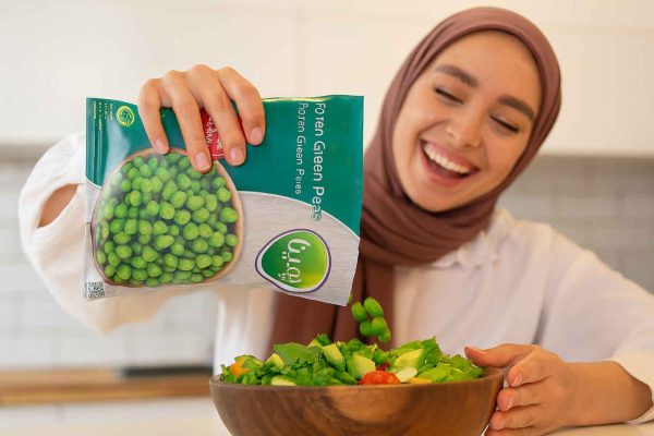 girl-pouring-frozen-green-peas-pemina-into-salad