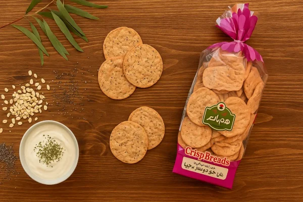 تصویر نان چیپسی جو دوسر و چیا هم‌دانه روی میز چوبی بیدی با دانه‌های چیا، جو دوسر و ماست نعناع خشک | سورن فودز