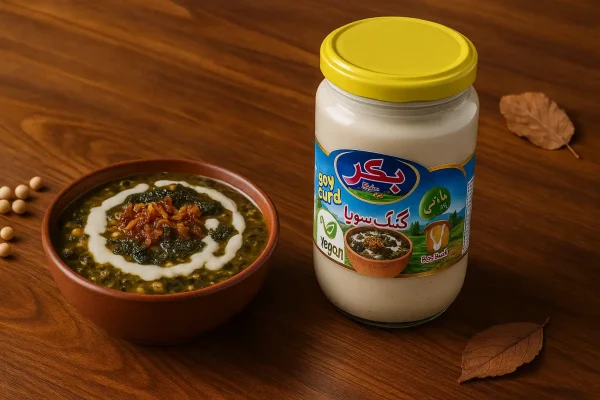 کشک سویا بکر کنار ظرف آش رشته با پیازداغ و نعناع داغ روی میز چوبی نارون