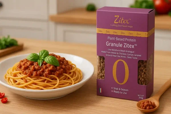 تصویر تبلیغاتی جایگزین گوشت چرخ کرده گیاهی زیتکس در کنار ظرف پاستا با سس گیاهی در بک‌گراند آشپزخانه
